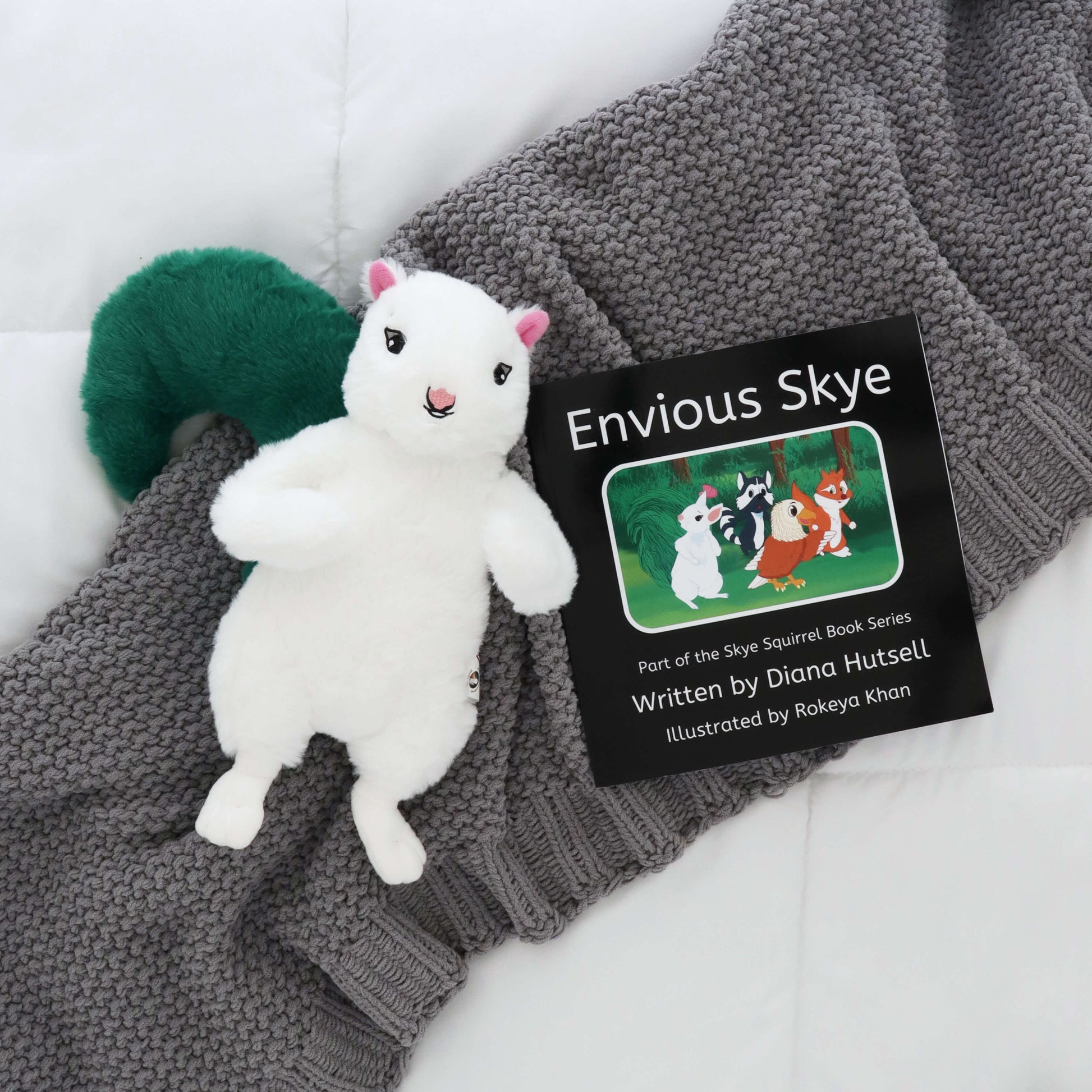 Envious Skye Book with Skye Squirrel with Green Stuffed Tail on a gray blanket