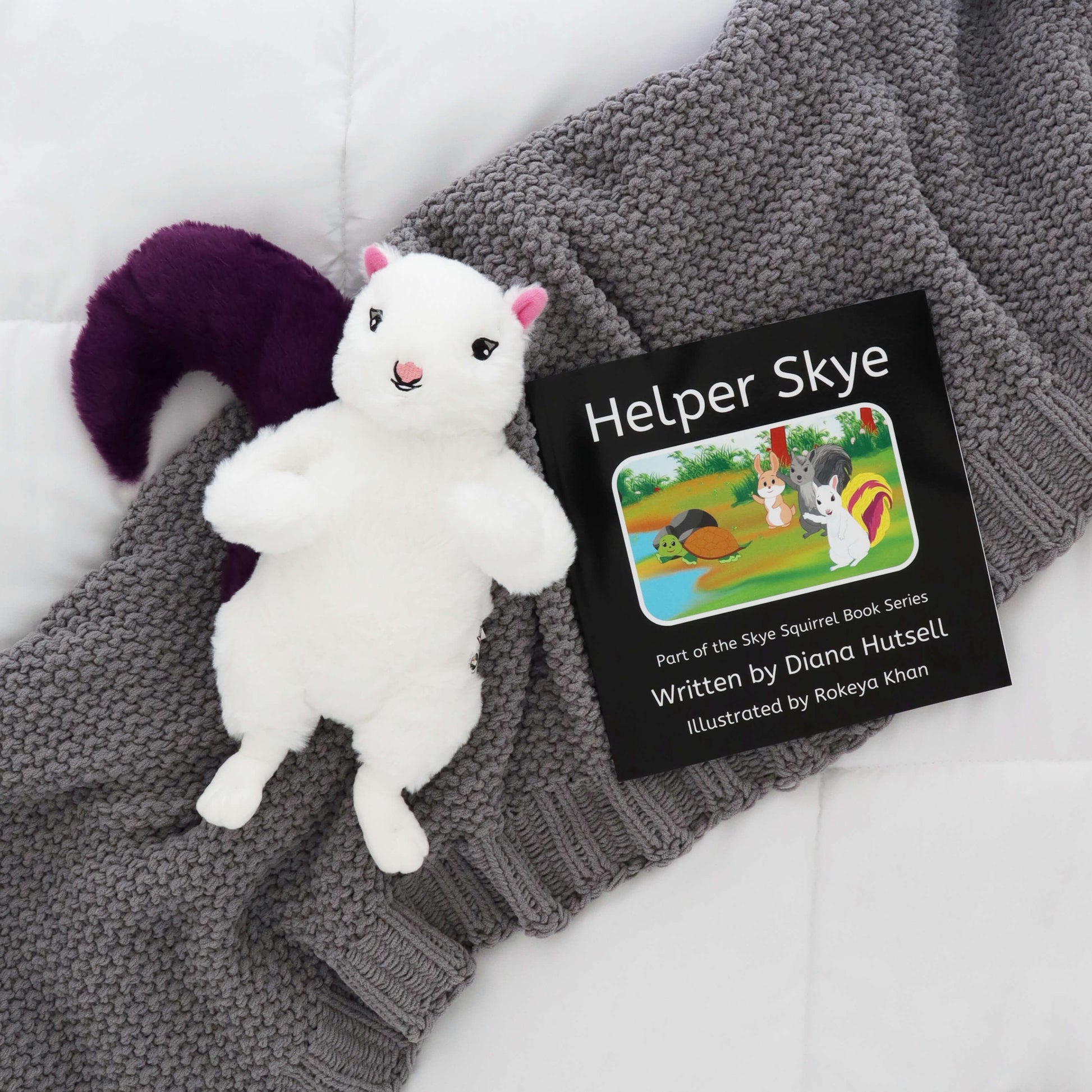 Helper Skye Book with Skye Squirrel with Purple Stuffed Tail on a gray blanket