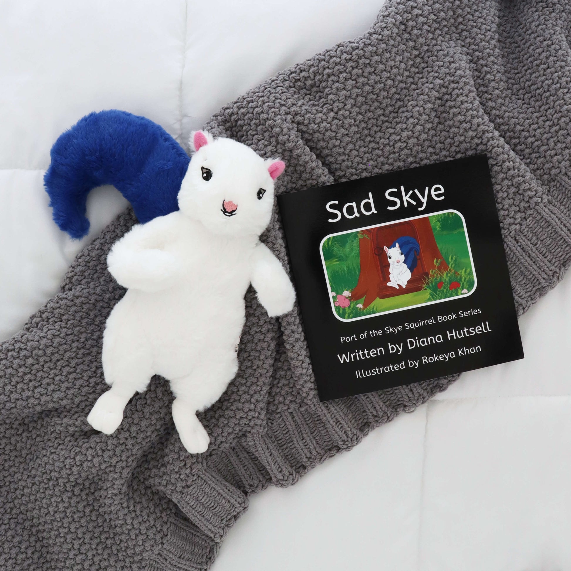 Sad Skye Book with Skye Squirrel with Blue Stuffed Tail on a gray blanket